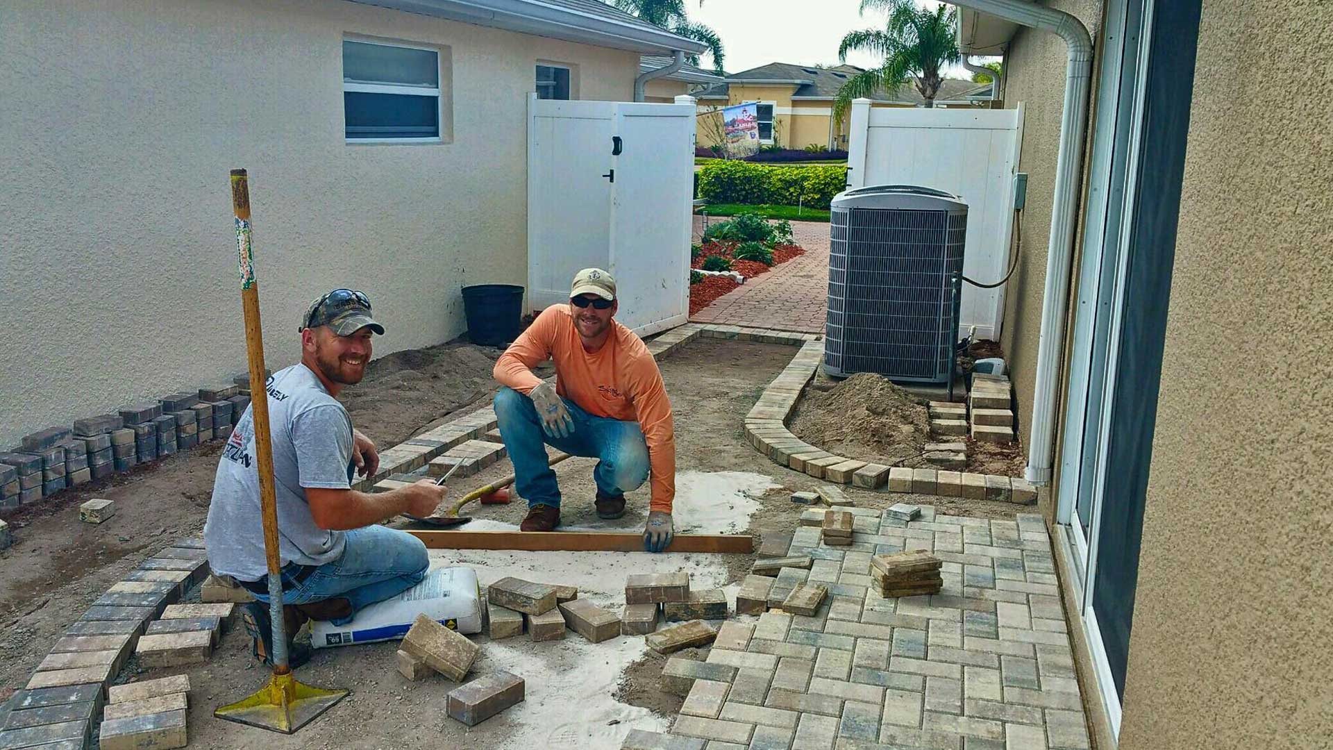 Two Tropical Temptations Landscaping employees installing a new hardscaping project.